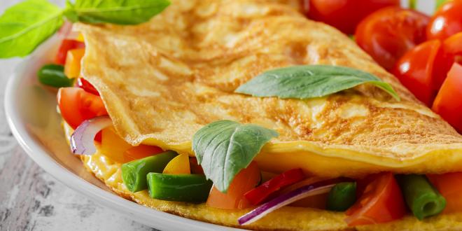 a perfectly-cooked omelet with veggies and chopped cherry tomatoes