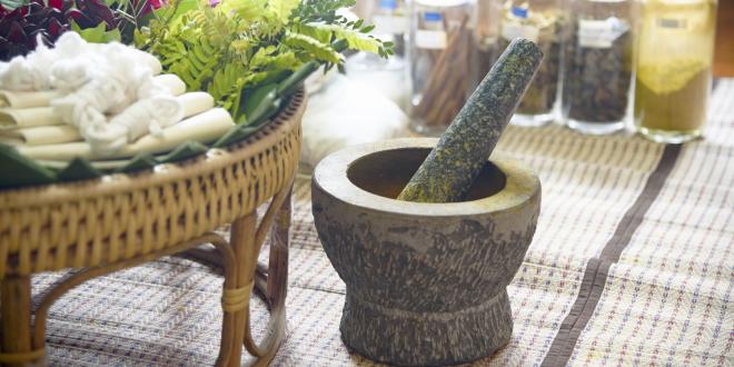 Ayurvedic herbal remedies in glass jars with a mortar and pestle.