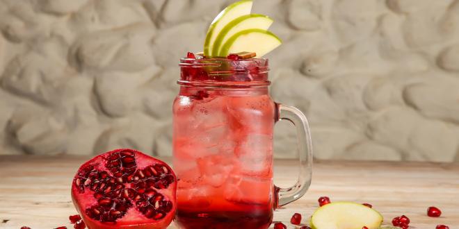 a glass of pomegranate mocktail garnished with pear slices