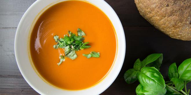 A bowl of roasted carrot soup sprinkled with herbs