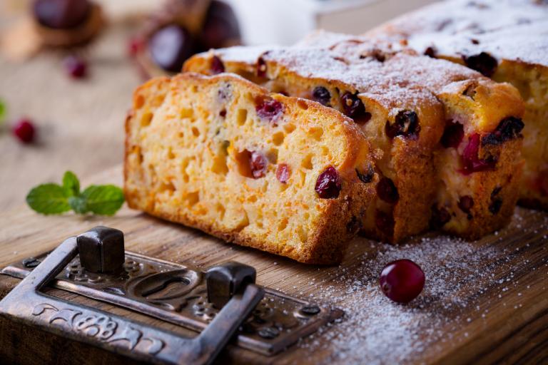 Homemade Pumpkin Cranberry Bread on a cutting board dusted with powdered sugar.