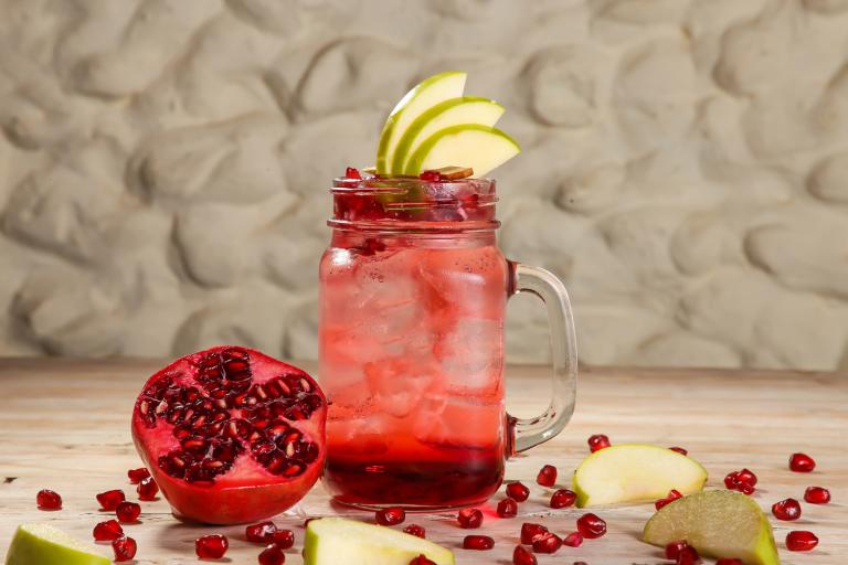 a glass of pomegranate mocktail garnished with pear slices